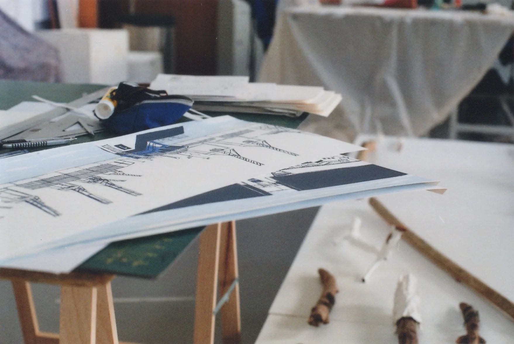 Photographie d'atelier avec plans, maquettes et table de travail.